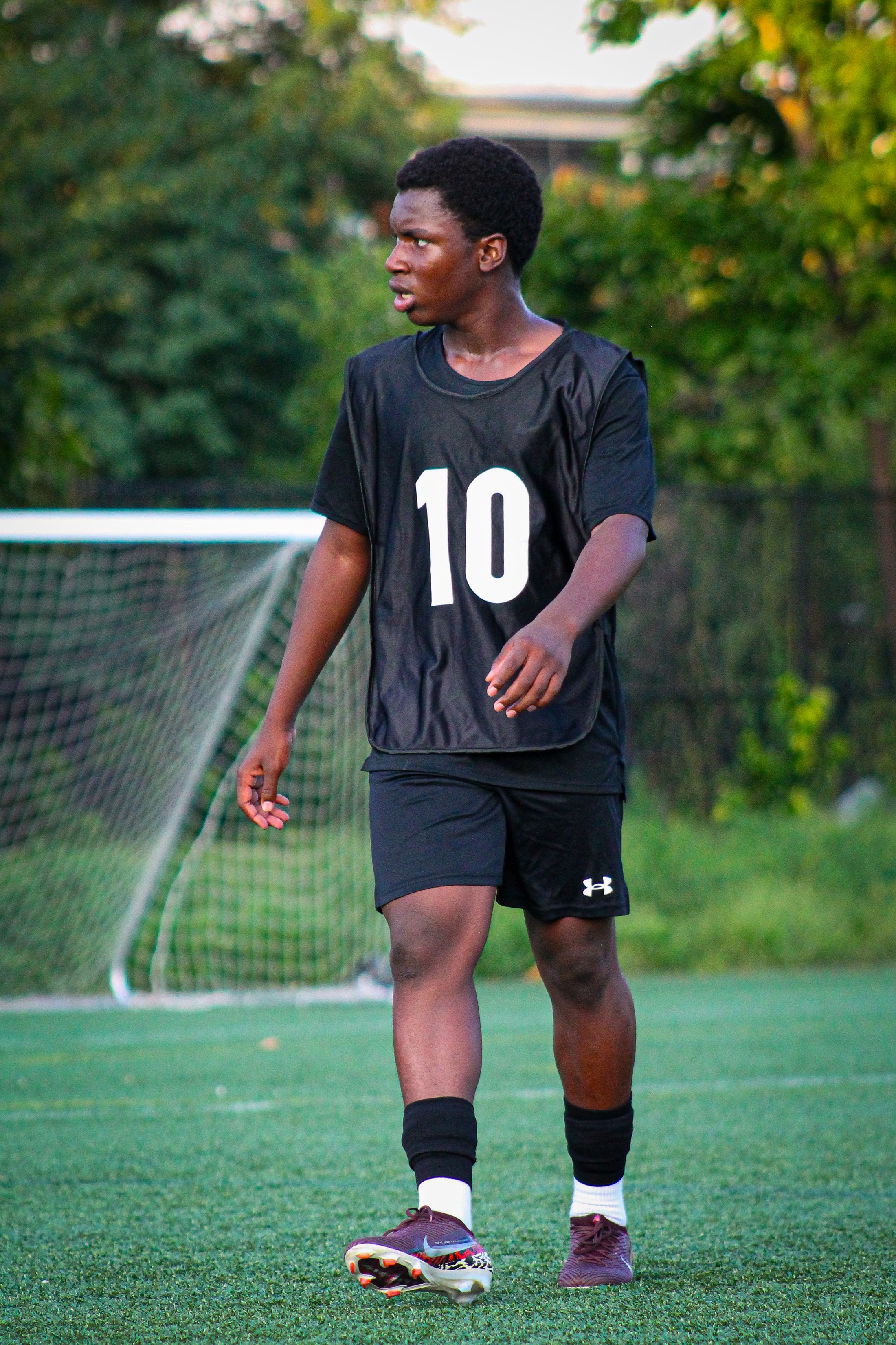A player in a black number ten bib standing on the pitch
