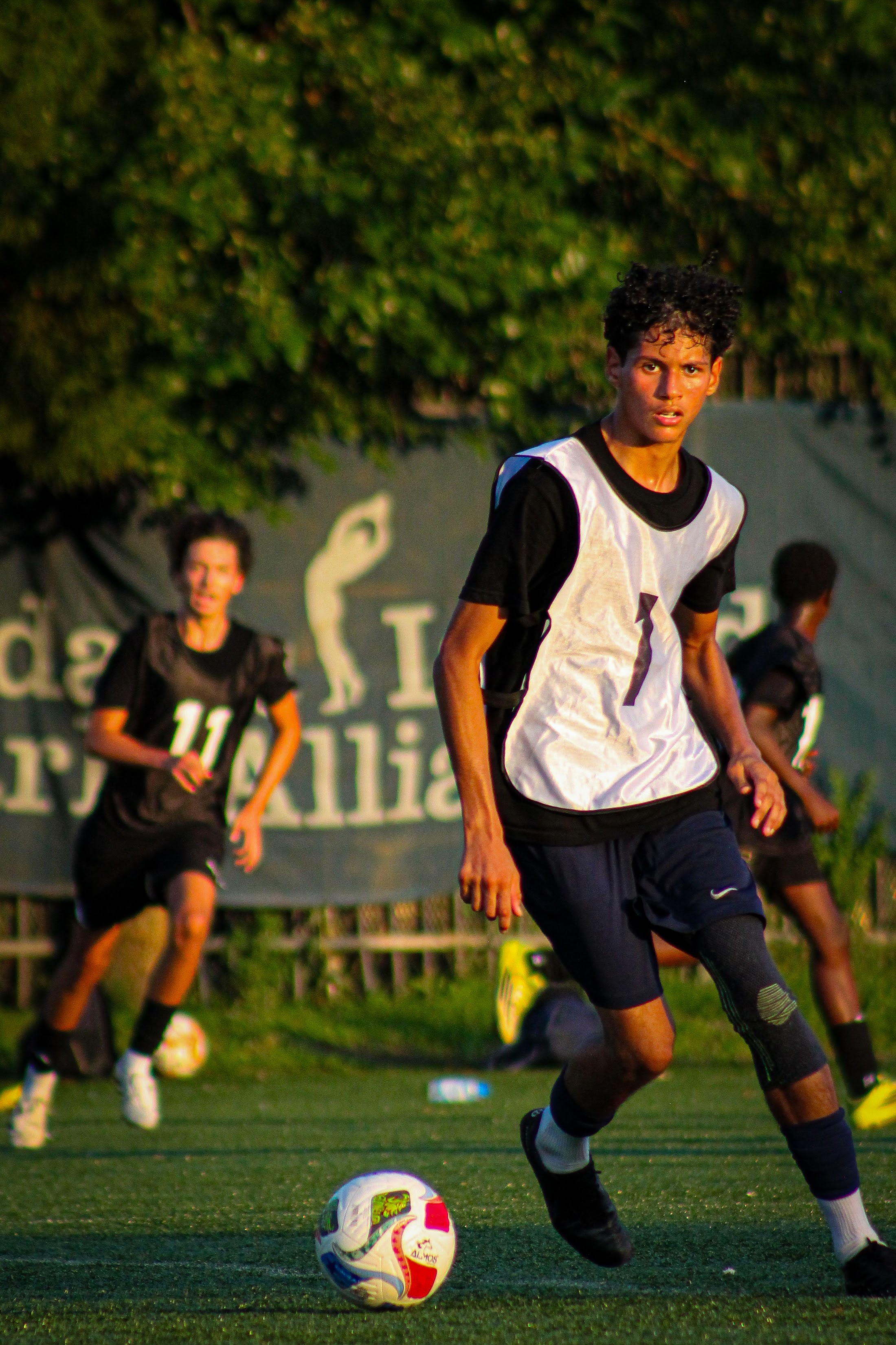 A player in a white bib dribbling the ball during a JOGA session
