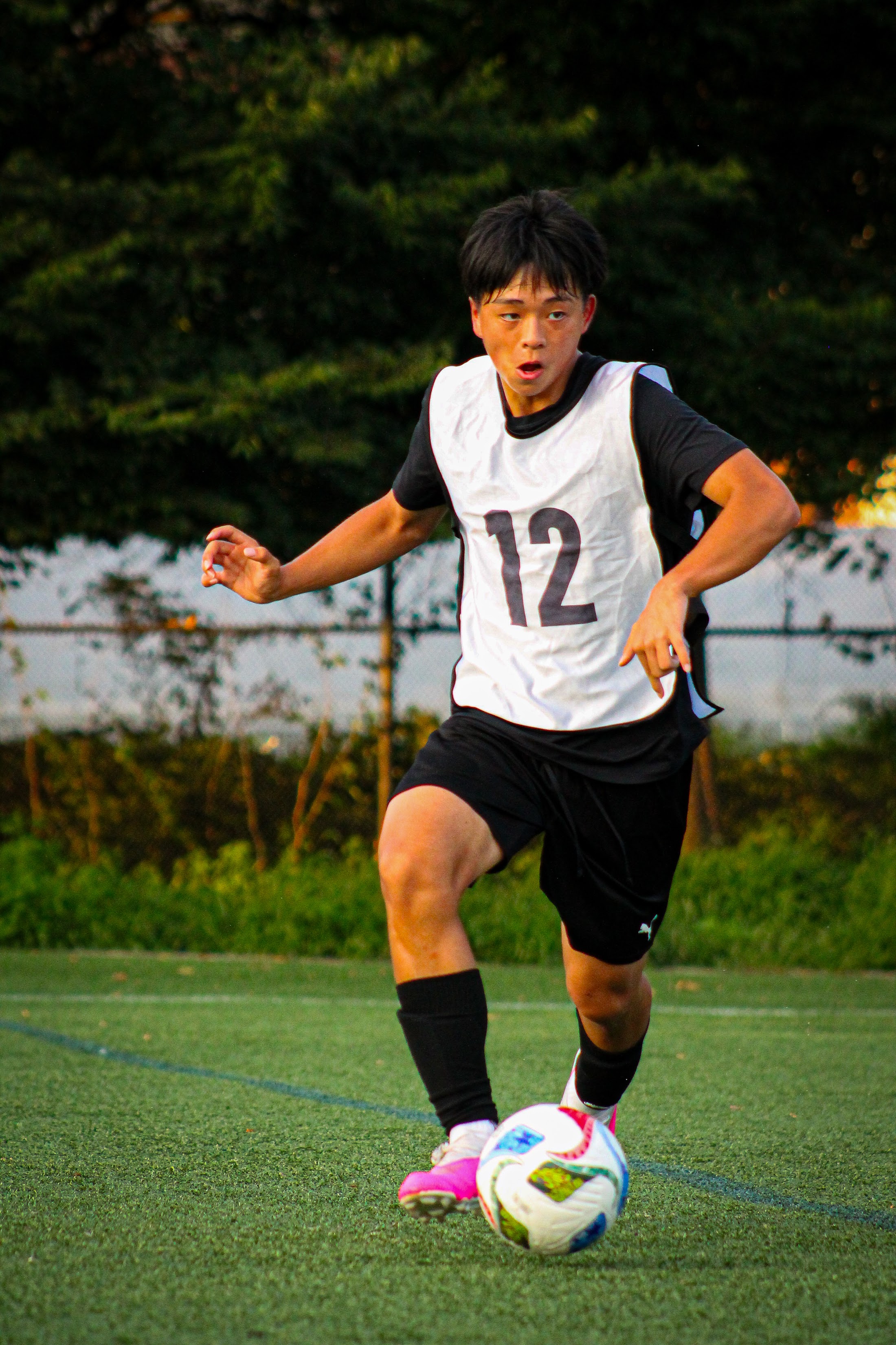 A player in a number twelve bib taking a touch