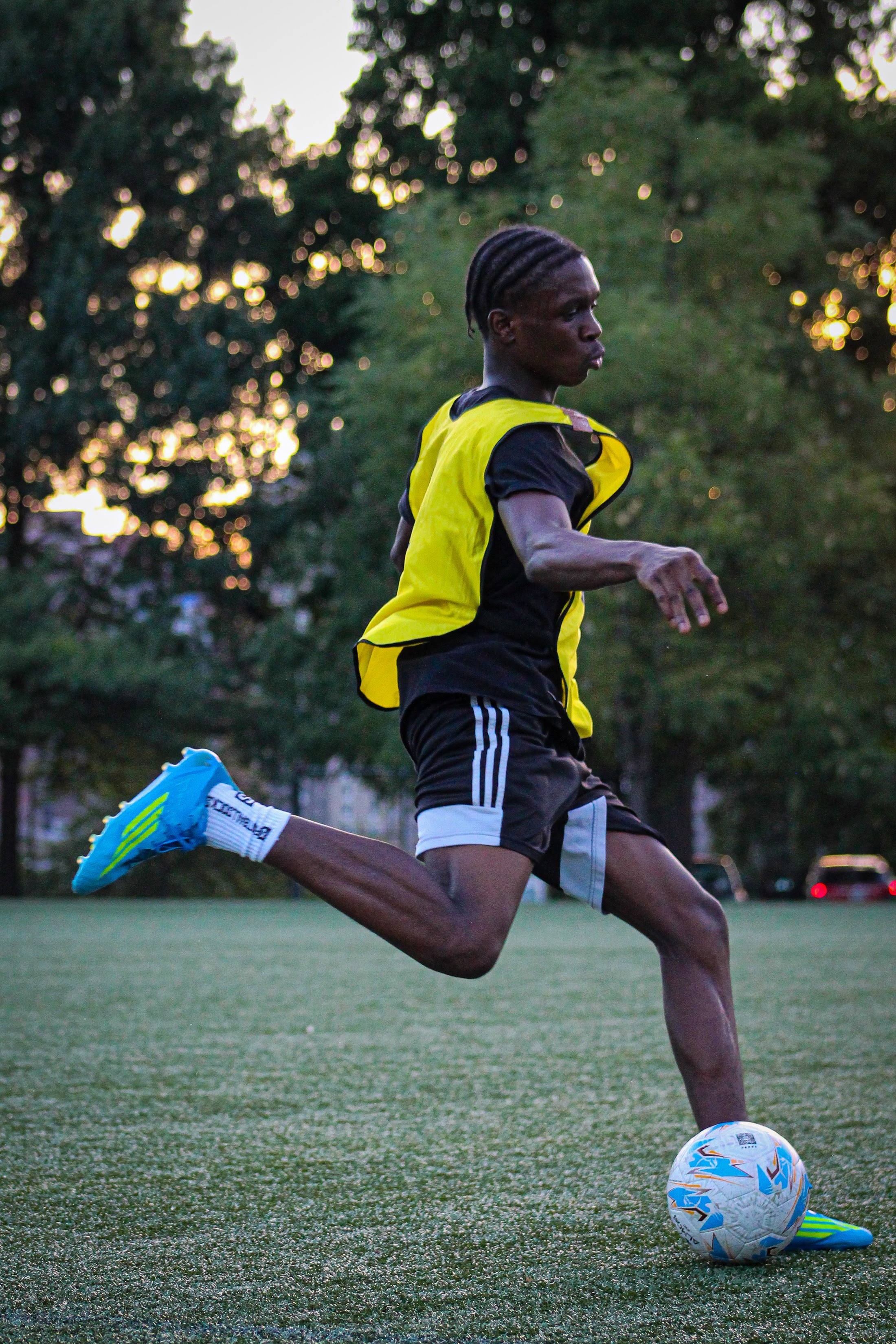 A player in a yellow bib striking the ball