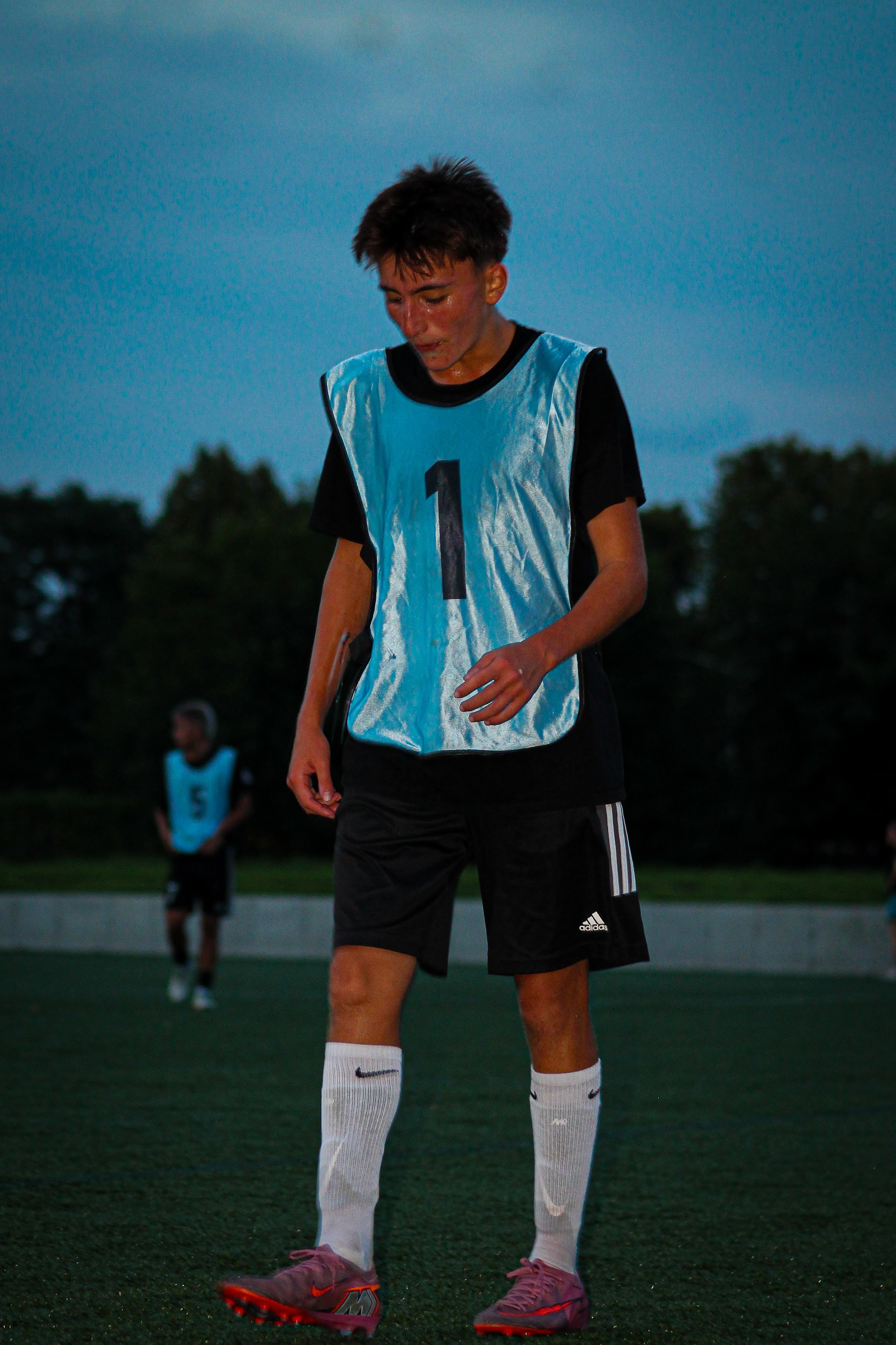 A player in a blue number eleven bib against a darkening sky