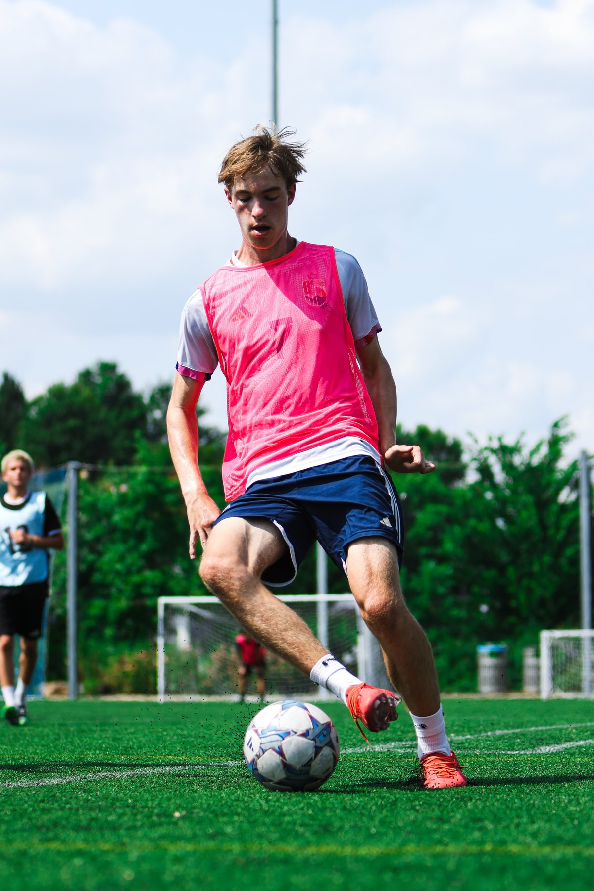 A player in a pink bib controlling the ball on the pitch